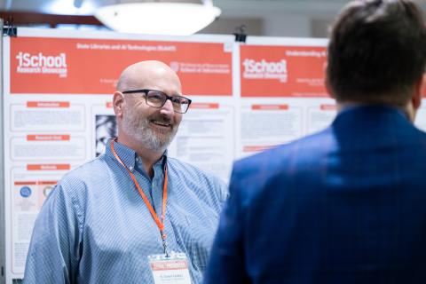 Man smiling in front of research poster