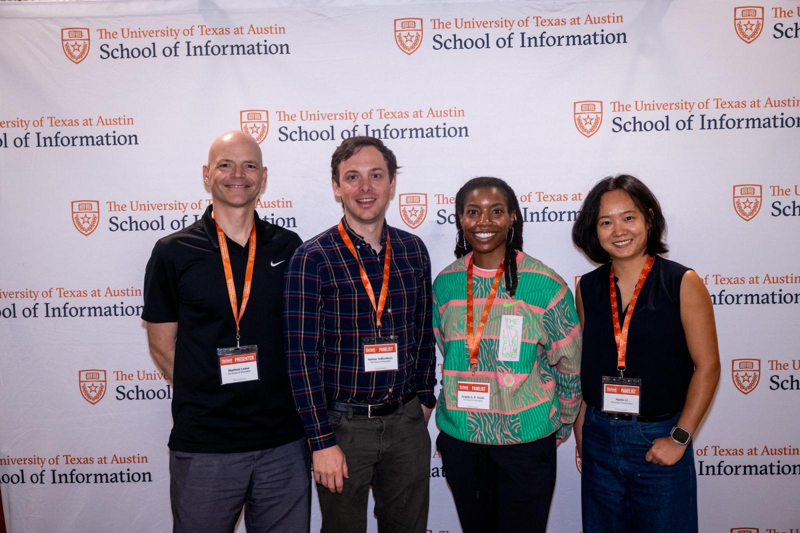 Four panelists posting in front of step and repeat