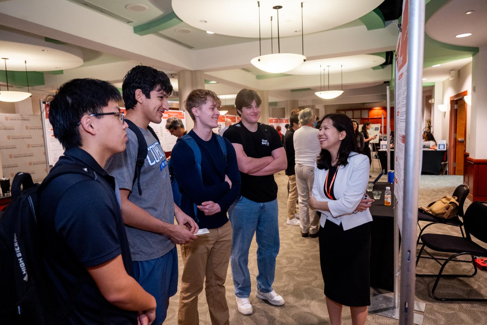 PhD student speaking to student attendees in front of poster