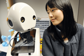 A picture of Dr.Min Kyung Lee sitting next to a robot