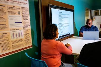 PhD students and faculty member sitting around a monitor watching an AI chatbot demo