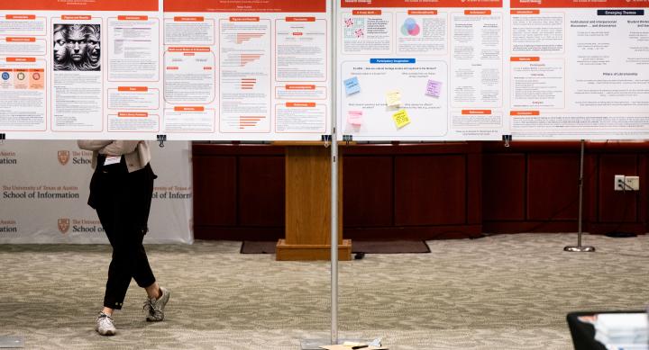 Person standing and looking at row of research posters