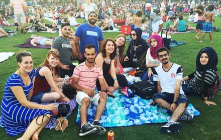A group of international students sit on a picnic blanket